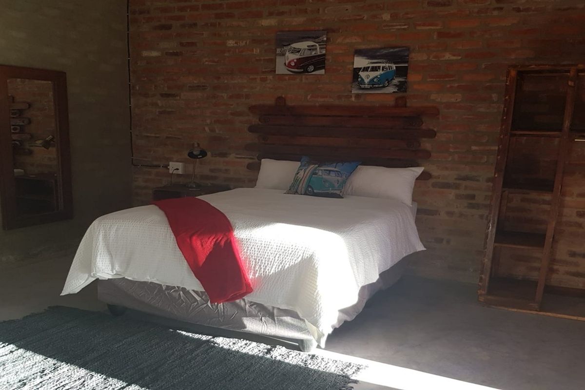 A rustic bedroom featuring an exposed brick feature wall and polished concrete flooring, creating an industrial-style living space.