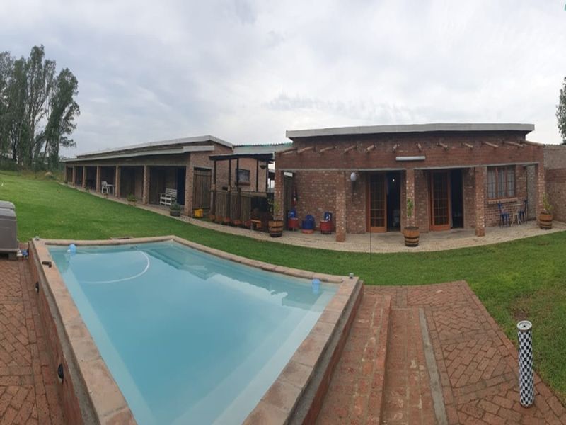Spacious outdoor entertainment area featuring a swimming pool, brick-paved patio, and an extensive exposed brick building facade with covered walkway.