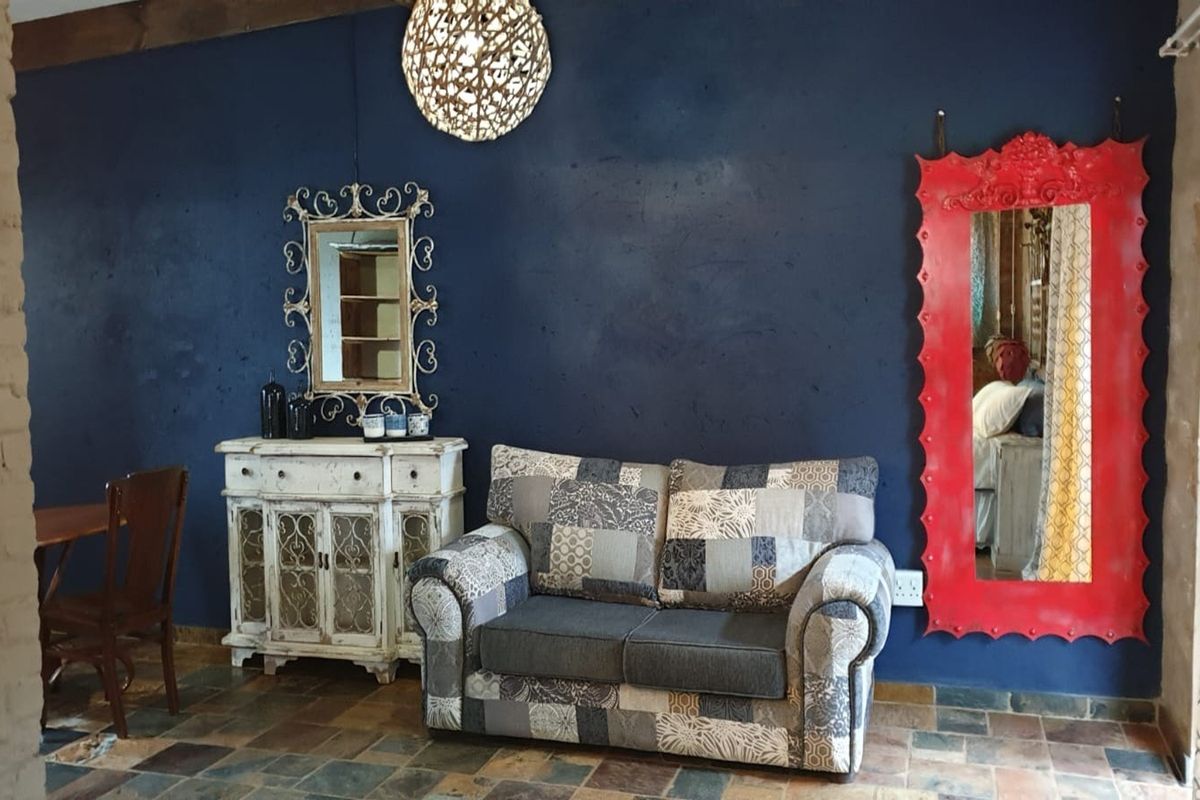 A living area featuring dark blue feature walls, rustic slate tile flooring, and exposed timber ceiling beams, offering a distinct characterful aesthetic.