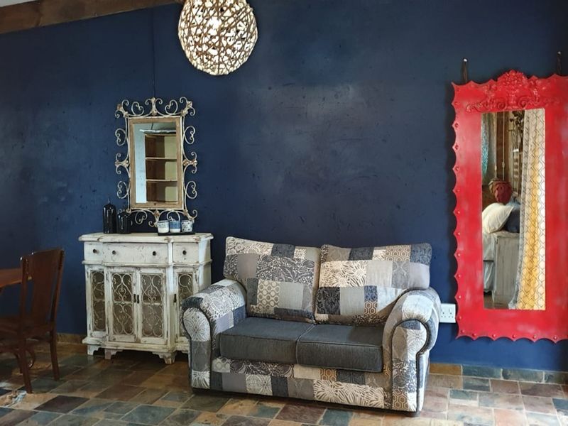 A living area featuring dark blue feature walls, rustic slate tile flooring, and exposed timber ceiling beams, offering a distinct characterful aesthetic.
