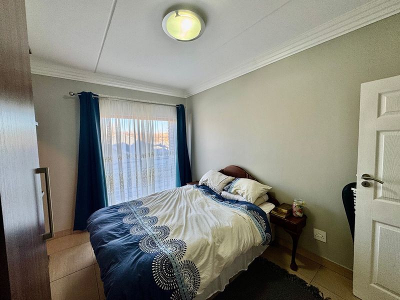 A functional bedroom featuring tiled flooring, built-in wardrobe storage, and a ceiling light, offering a neutral base for personalization.