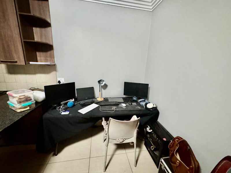 A functional home office space featuring built-in cabinetry and tiled flooring, suitable for a dedicated workspace or study area.