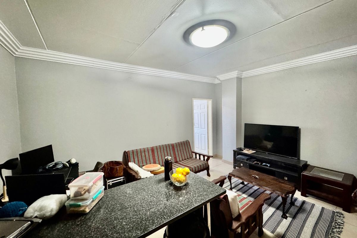 Open plan living area featuring a granite breakfast bar, crown molding, and neutral wall finishes, providing a functional space for daily living.