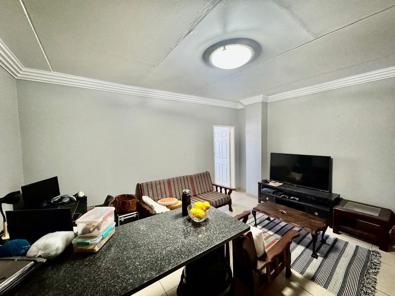 Open plan living area featuring a granite breakfast bar, crown molding, and neutral wall finishes, providing a functional space for daily living.