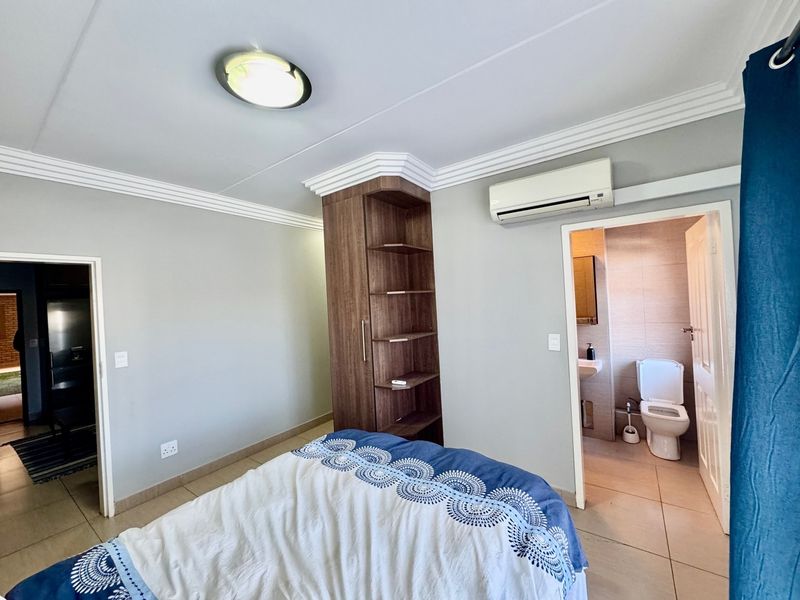 Bedroom featuring tiled flooring, built-in shelving, split-system air conditioning, and direct access to an en-suite bathroom.