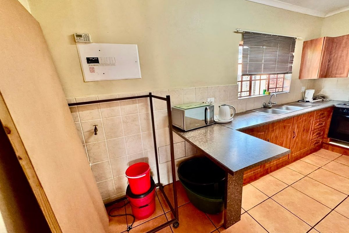 A functional kitchen featuring laminate countertops, a double basin sink, tiled backsplash, and built-in cabinetry with ceramic floor tiles.
