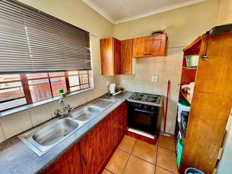 Compact kitchen featuring wooden cabinetry, laminate countertops, a double bowl sink, and a built-in electric oven with hob.