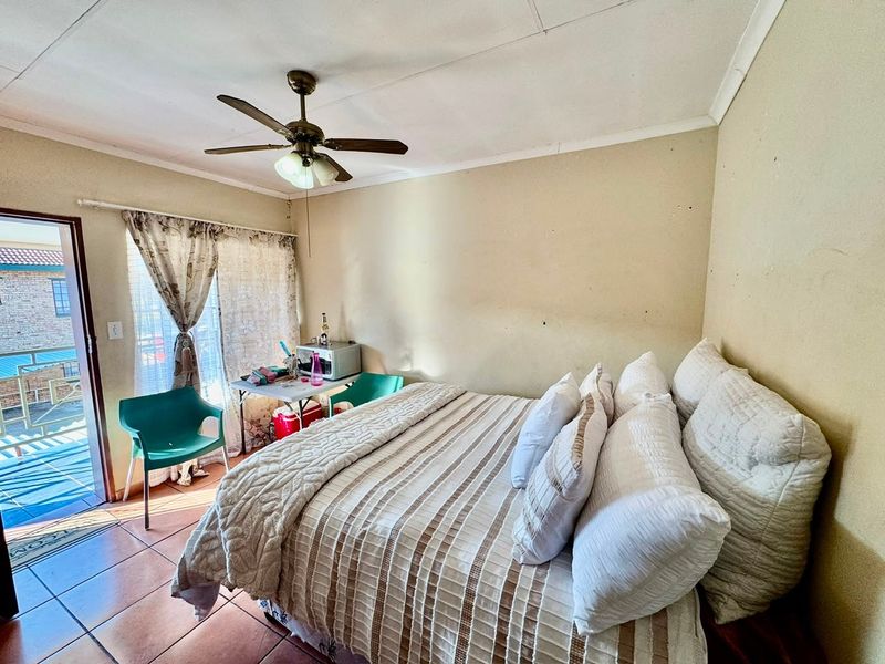 A bedroom featuring tiled flooring, a ceiling fan, and direct access to an outdoor balcony through a sliding glass door.