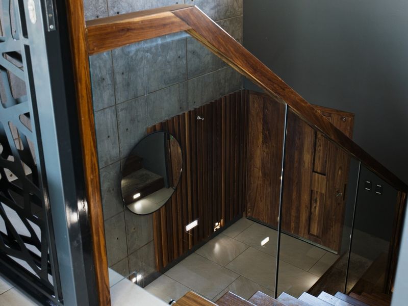 Modern staircase area featuring a glass balustrade, timber handrail, concrete wall panels, and elegant timber slat wall cladding with recessed lighting.