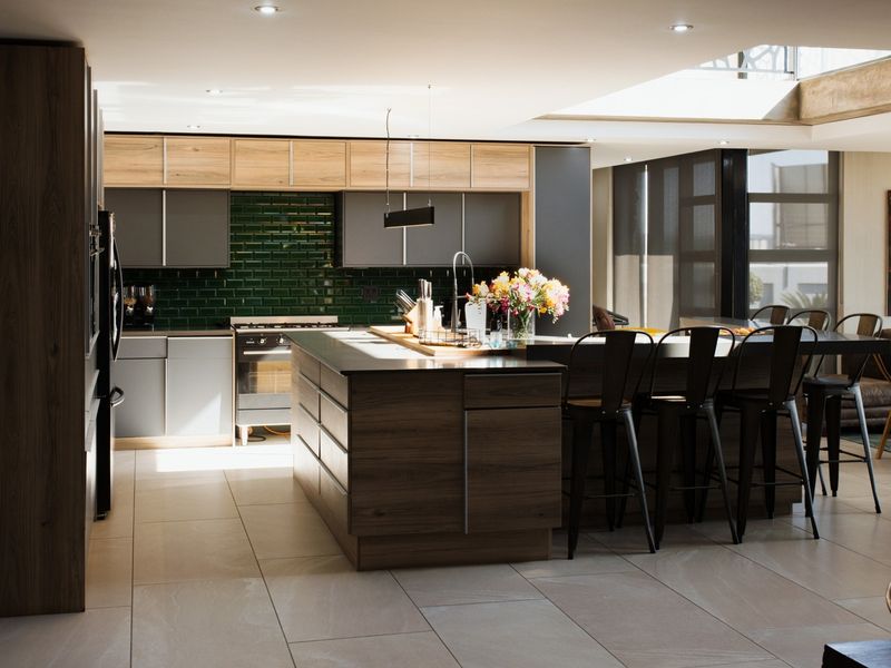 Modern open-plan kitchen featuring a large central island, sleek cabinetry, tiled flooring, and a bright skylight, creating a spacious and contemporary living environment.