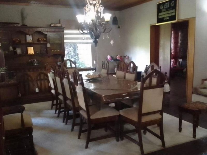 A traditional dining room featuring a timber ceiling, central chandelier, and classic wooden door frames, providing a formal space for family meals.