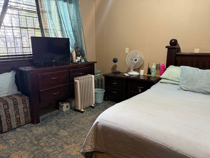 A bedroom featuring a window with security bars, providing natural light and a functional layout.
