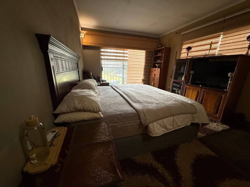 A spacious bedroom featuring built-in shelving, window blinds, and a security gate, offering a comfortable and functional living space.