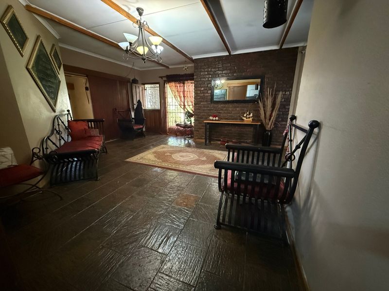 Spacious living area featuring rustic slate tile flooring, exposed timber ceiling beams, and a prominent exposed brick feature wall.