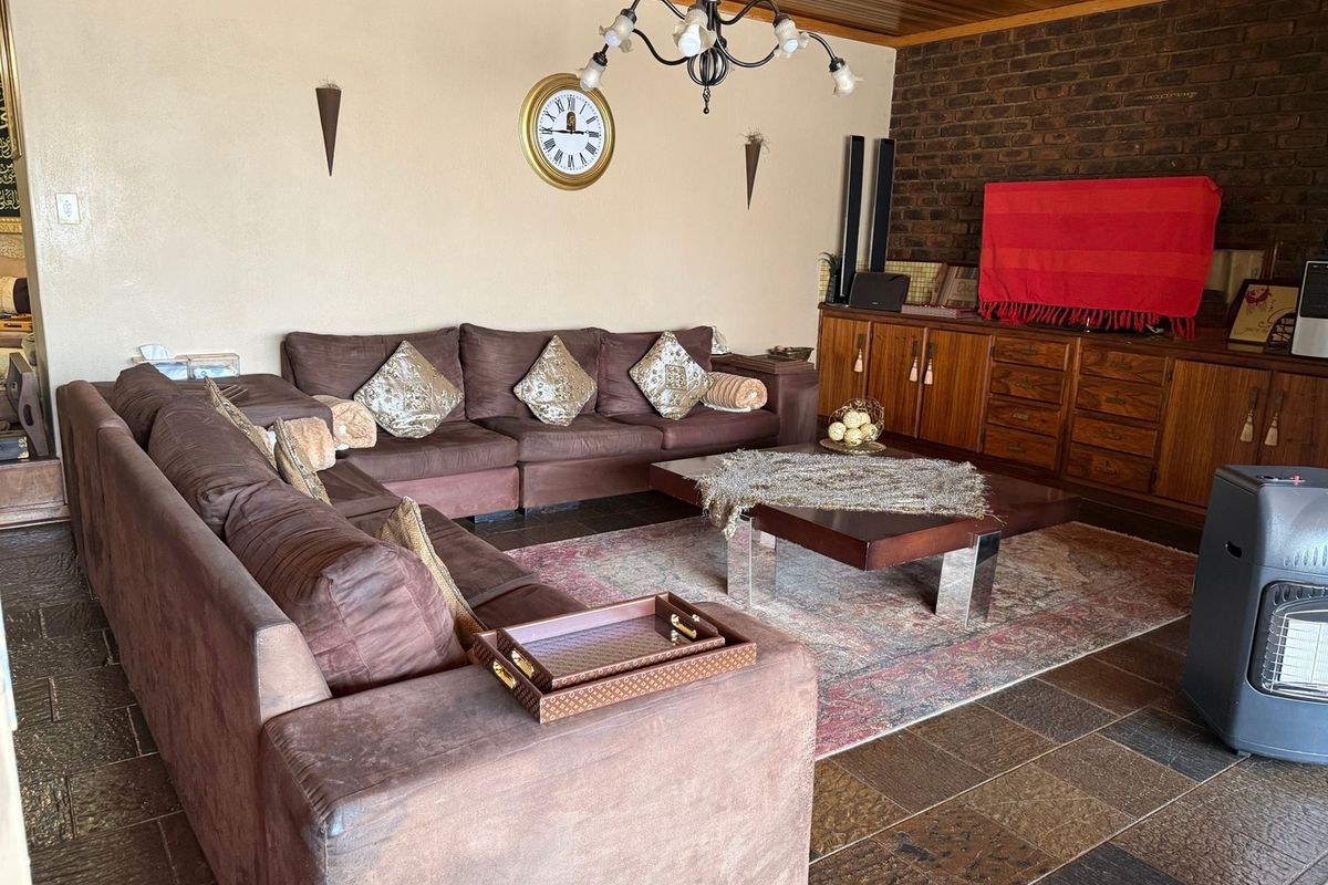 A living room featuring exposed brickwork, timber ceiling paneling, and tiled flooring, complemented by built-in cabinetry.