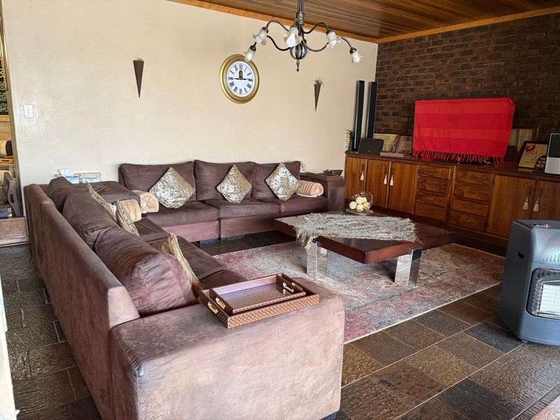 A living room featuring exposed brickwork, timber ceiling paneling, and tiled flooring, complemented by built-in cabinetry.