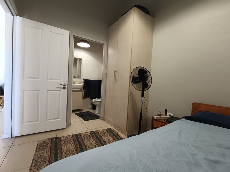 A bedroom featuring tiled flooring, a built-in wardrobe, and direct access to an en-suite bathroom.