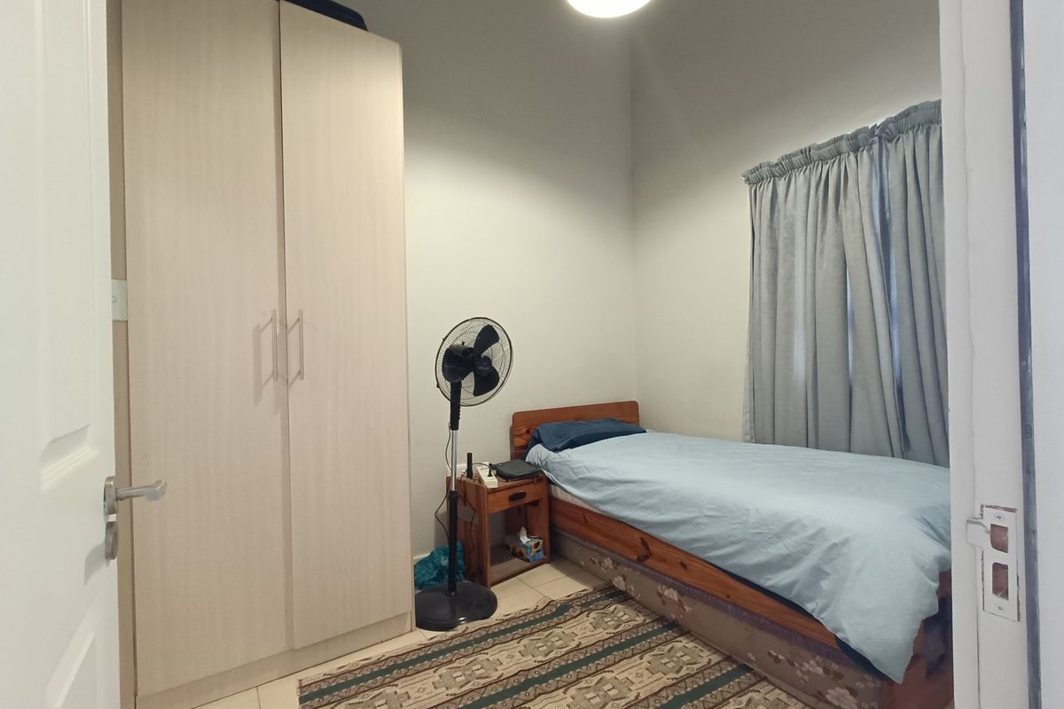 A functional bedroom featuring a built-in wardrobe and tiled flooring, offering a neutral space ready for personalization.