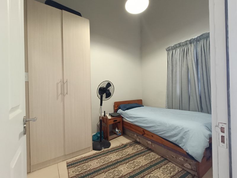 A functional bedroom featuring a built-in wardrobe and tiled flooring, offering a neutral space ready for personalization.