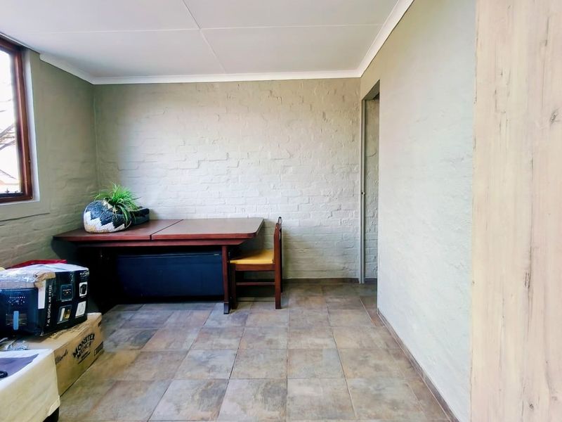 A living area featuring tiled flooring, painted brick walls, and a coved ceiling, providing a neutral foundation for interior design updates.