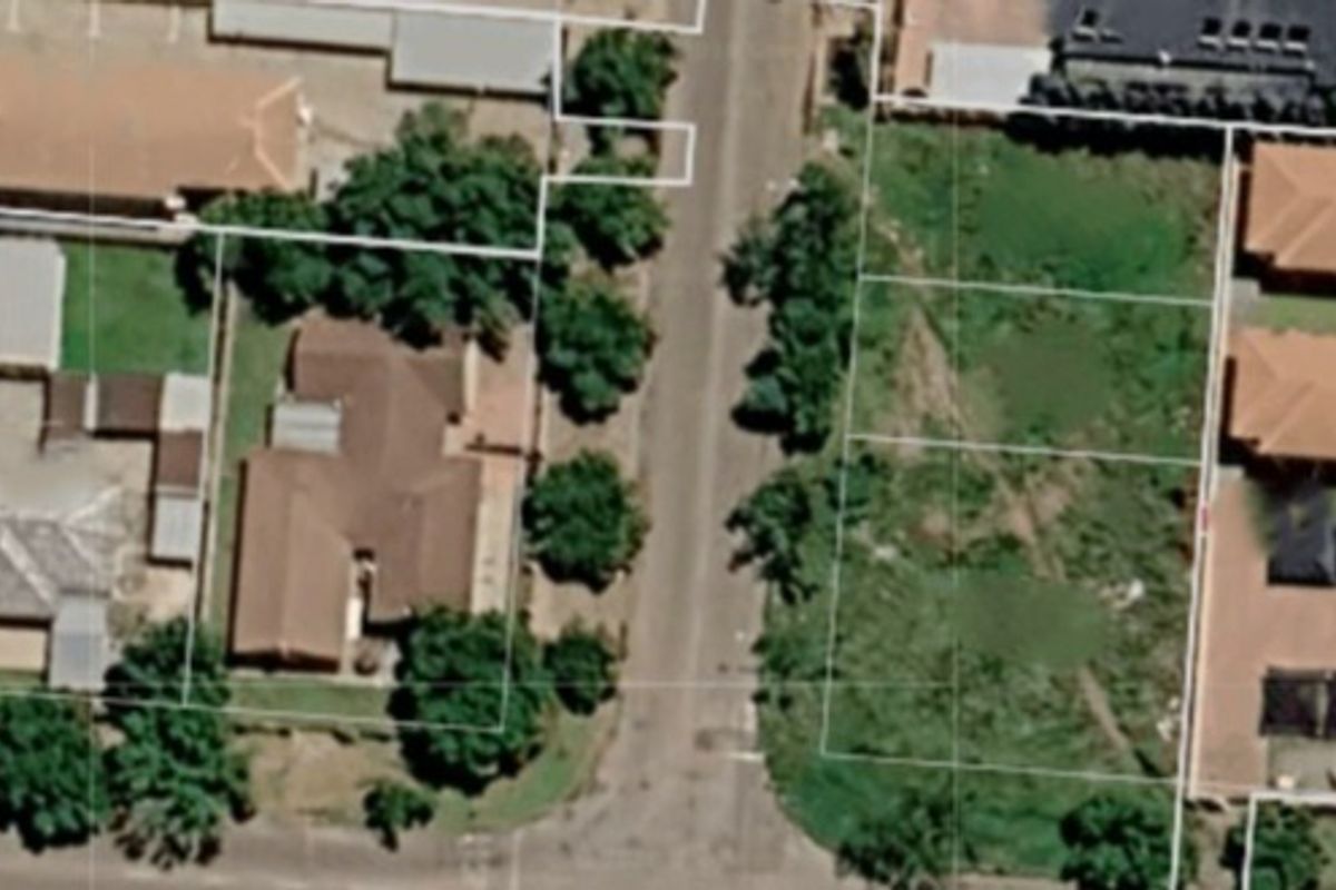 An aerial view showing a vacant residential plot situated within an established neighborhood, highlighting the available land and surrounding property layout.