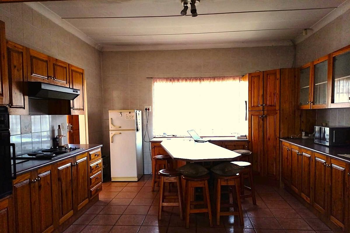 A spacious kitchen featuring traditional wooden cabinetry, a central island, tiled flooring, and a functional layout with built-in appliances.