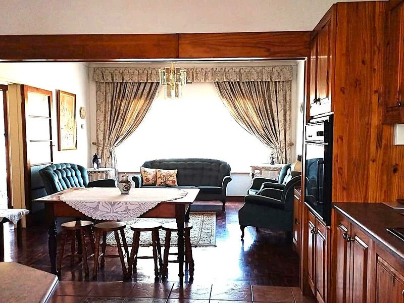 Open-plan kitchen and living area featuring traditional wooden cabinetry, built-in appliances, and parquet flooring, creating a warm and connected living space.