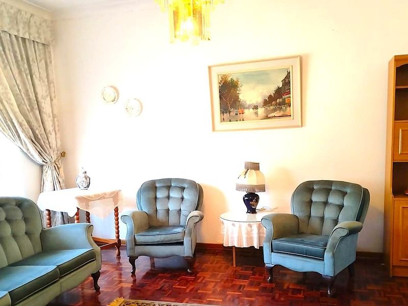 A traditional living room featuring classic parquet flooring and a central ceiling light fixture, offering a warm and established atmosphere.