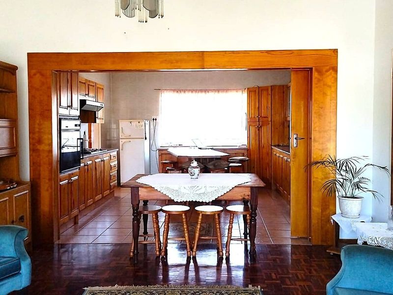 Open plan living and kitchen area featuring traditional wooden cabinetry, built-in oven, and a combination of parquet and tiled flooring.