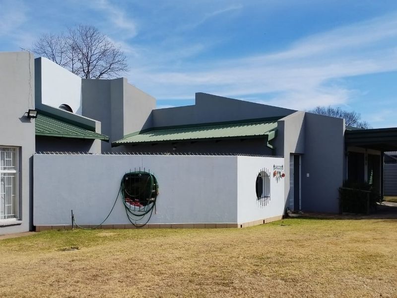Front view of a modern-style house featuring a metal roof, security perimeter wall, and an attached carport.