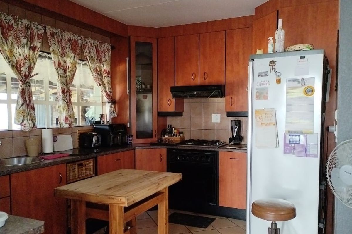 A functional kitchen featuring wood-finish cabinetry, tiled backsplash, gas hob with extractor, and integrated oven, offering a traditional layout with ample storage space.
