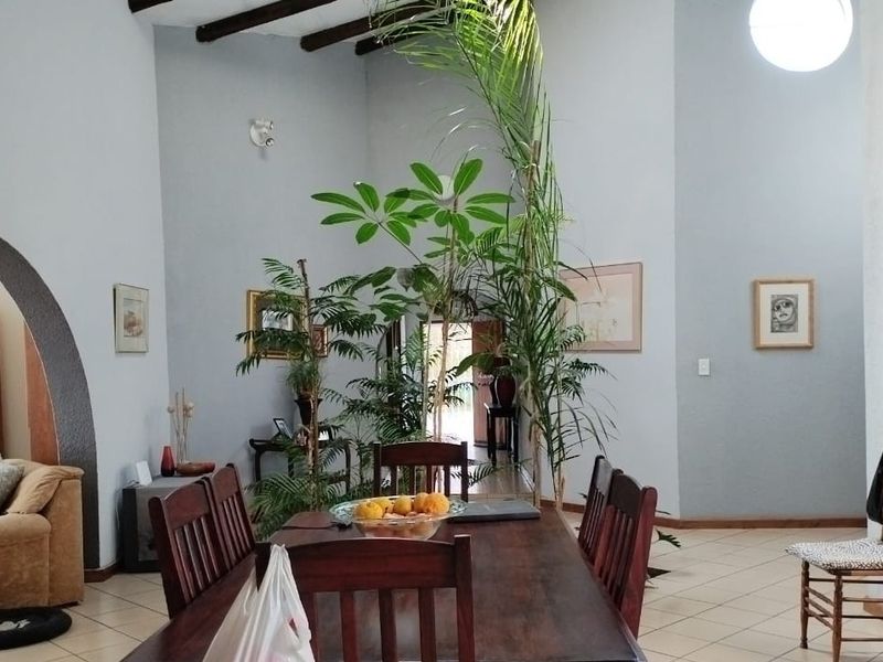 Spacious living area featuring high ceilings with exposed timber beams, tiled flooring, and a distinctive arched architectural detail.