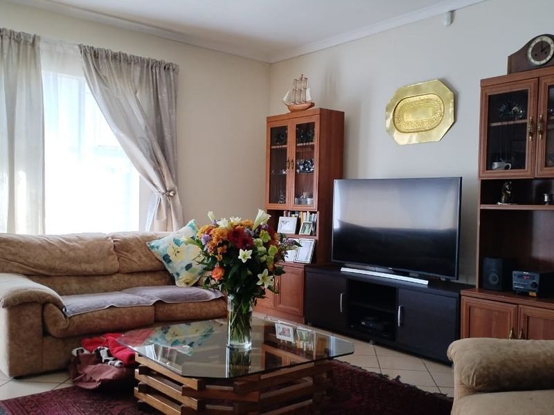 A comfortable living room featuring tiled flooring and classic coving, providing a functional and well-lit space for relaxation.