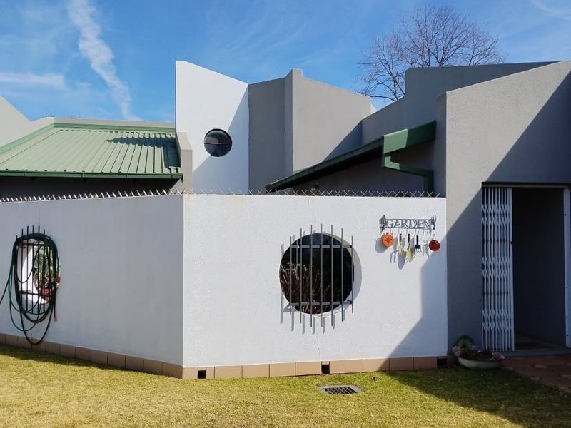Rear exterior view of the property featuring a modern architectural design with a circular window, security gate, and well-maintained exterior walls.
