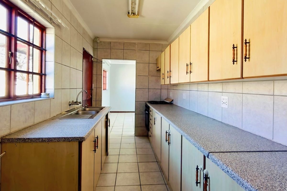A functional galley-style kitchen featuring laminate cabinetry, tiled surfaces, and built-in cooking appliances, offering a clean space ready for modern updates.