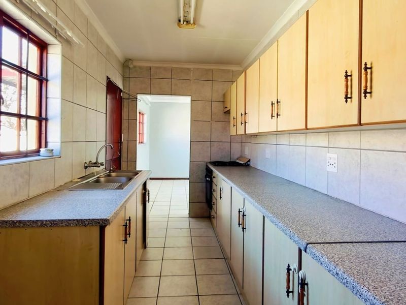 A functional galley-style kitchen featuring laminate cabinetry, tiled surfaces, and built-in cooking appliances, offering a clean space ready for modern updates.