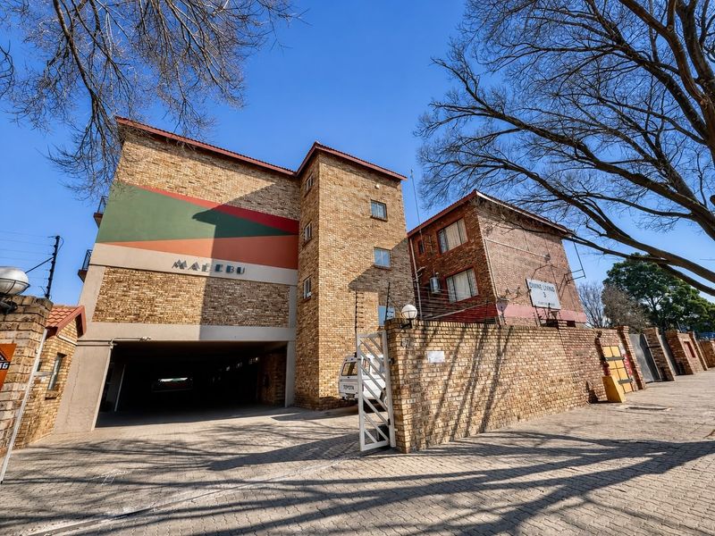 Front elevation of the Malebu apartment complex featuring face brick construction, secure gated access, and covered parking facilities.