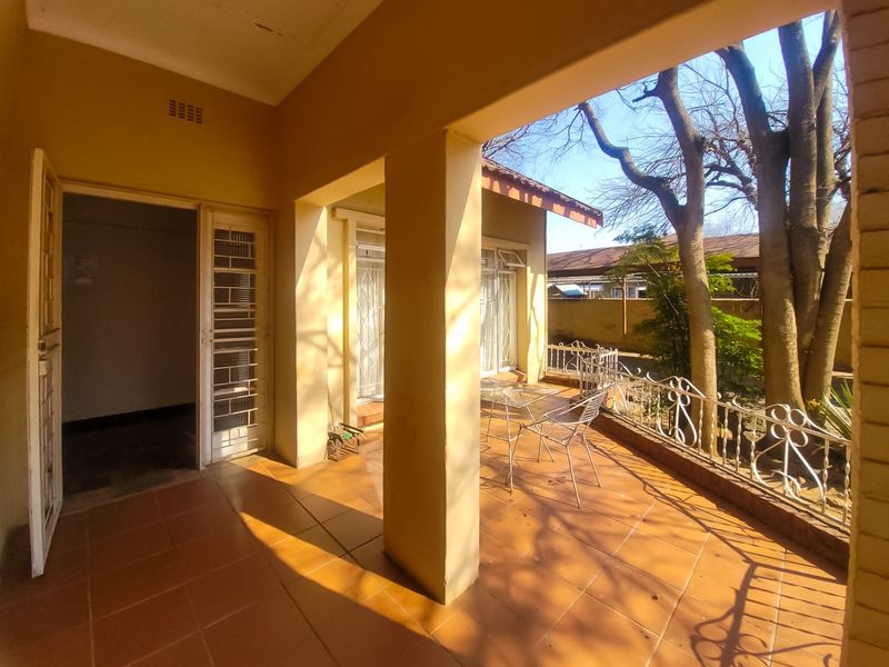 A covered patio area featuring tiled flooring and a decorative wrought iron balustrade, providing direct access to the garden.