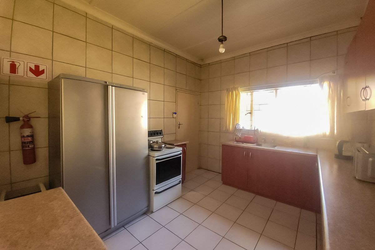 A functional kitchen featuring tiled walls and flooring, built-in cabinetry, a sink, and a freestanding stove, offering potential for modernization.