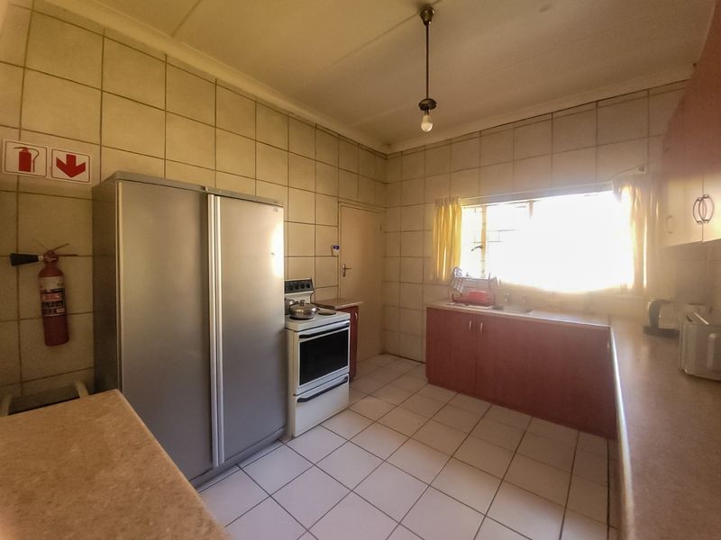 A functional kitchen featuring tiled walls and flooring, built-in cabinetry, a sink, and a freestanding stove, offering potential for modernization.