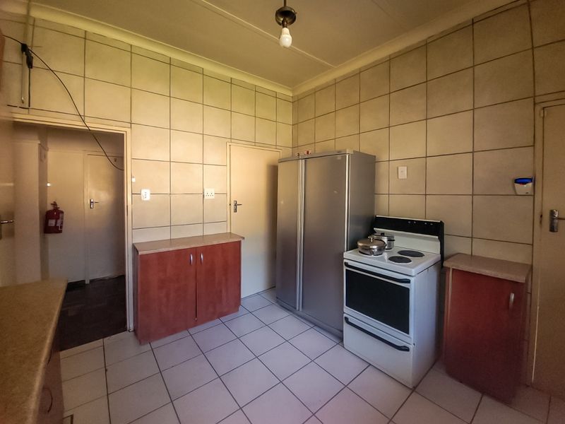 A functional kitchen featuring tiled walls and flooring, built-in cabinetry, and a freestanding stove, requiring cosmetic updates and electrical maintenance.