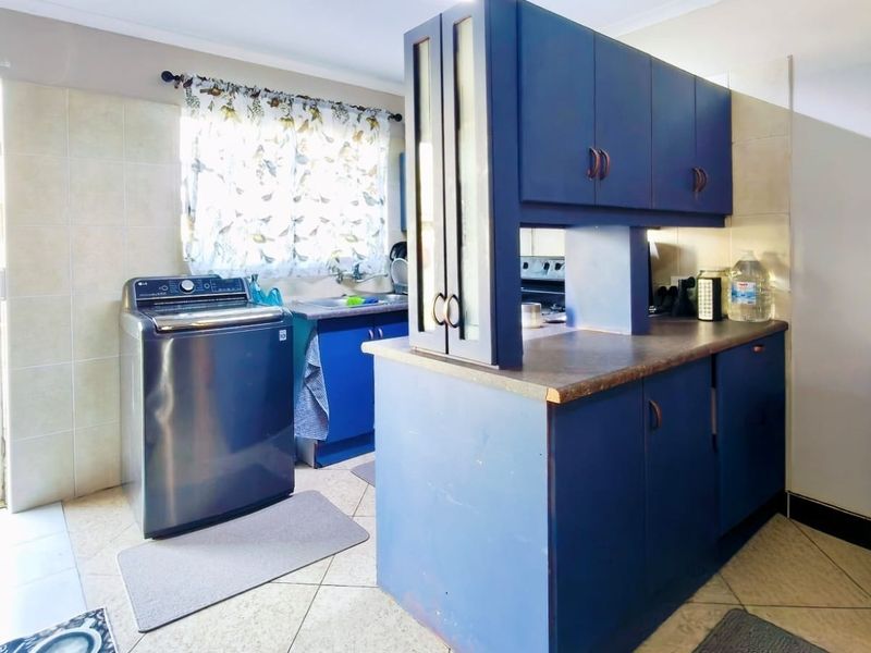 A functional kitchen featuring blue built-in cabinetry, laminate countertops, tiled backsplash, and direct access to an outdoor area.