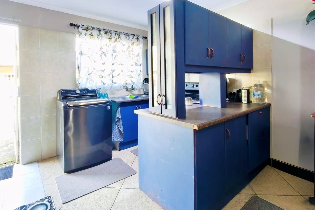 A functional kitchen featuring blue built-in cabinetry, laminate countertops, tiled backsplash, and direct access to an outdoor area.