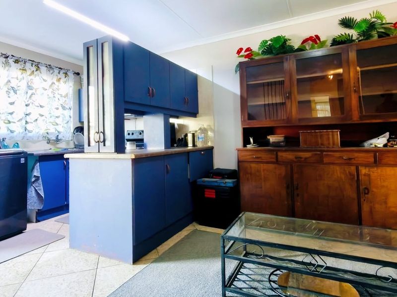 Open plan kitchen and living area featuring blue cabinetry, tiled flooring, and a large wooden display unit.