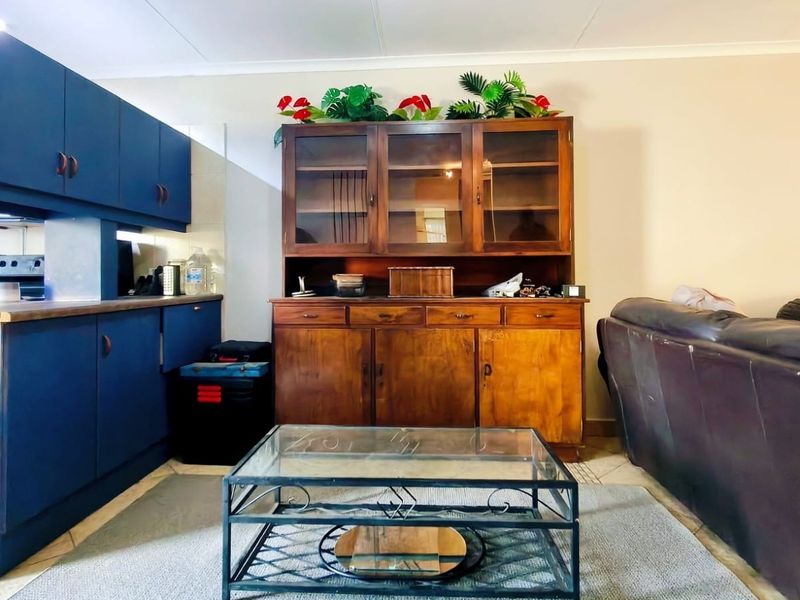 Open plan living area featuring blue built-in kitchen cabinetry, tiled flooring, and a neutral wall finish.
