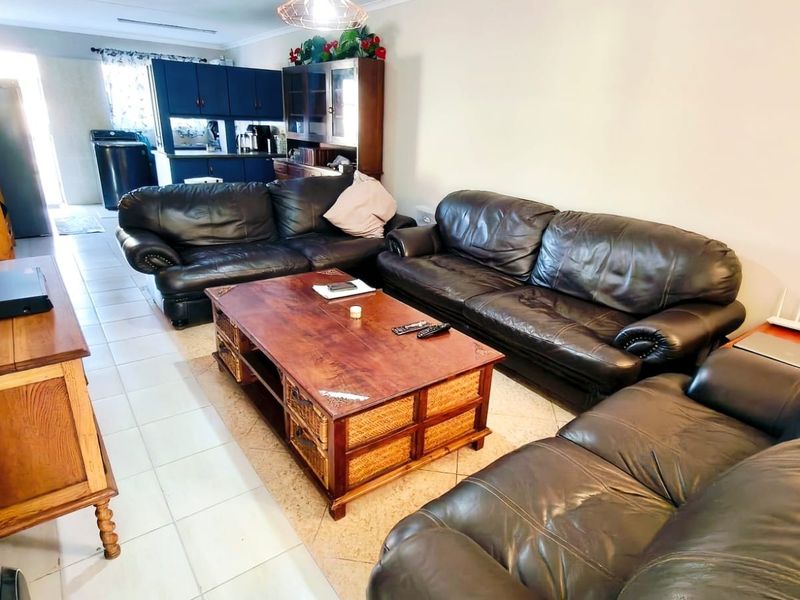 Open plan living area featuring tiled flooring and a view through to the kitchen space with built-in cabinetry.