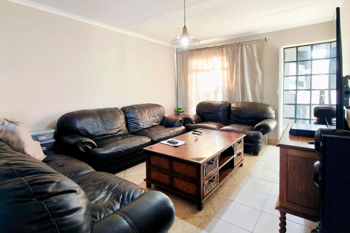 A comfortable living room featuring tiled flooring, a pendant light fixture, and a security gate leading to the exterior.