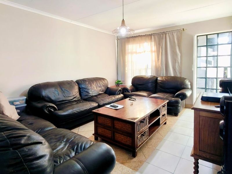 A comfortable living room featuring tiled flooring, a pendant light fixture, and a security gate leading to the exterior.