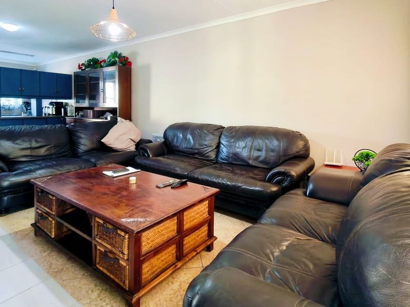 Open-plan living area featuring tiled flooring, coved ceilings, and an integrated kitchen space with dark cabinetry.