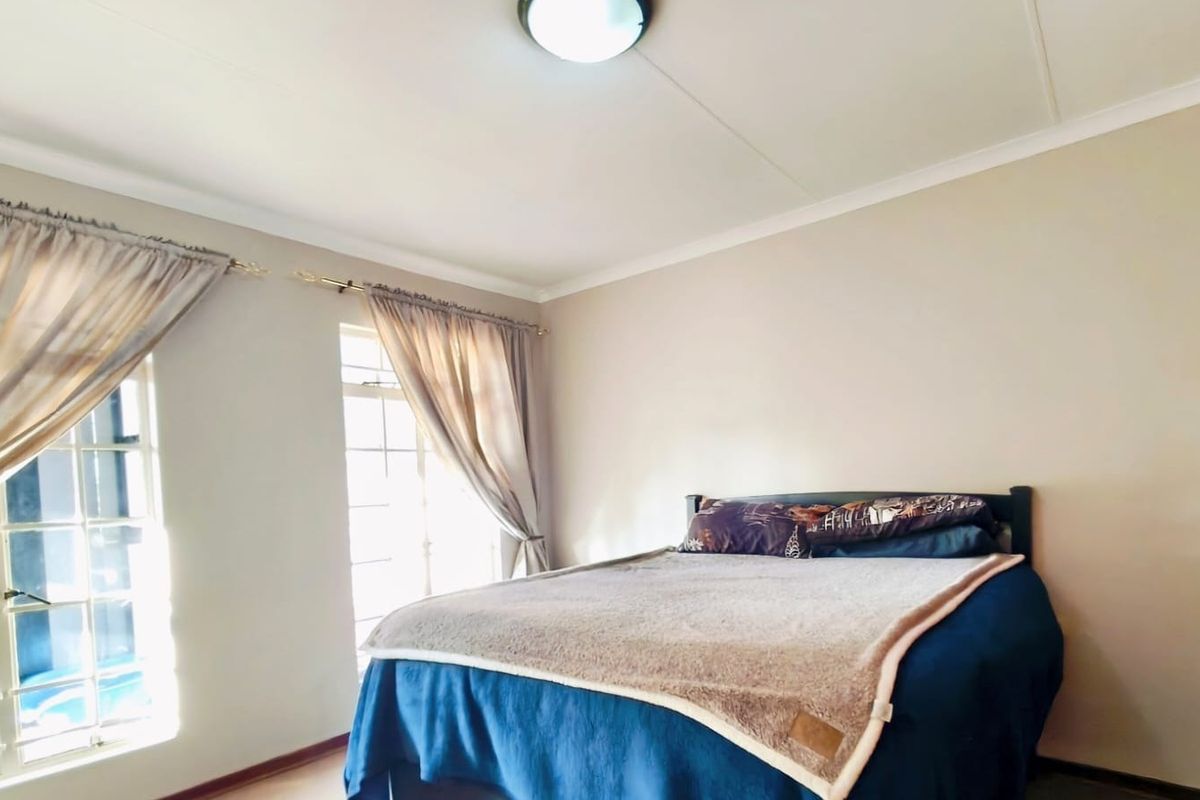 A well-lit bedroom featuring neutral walls, coved ceilings, and direct access to the exterior through classic french doors.